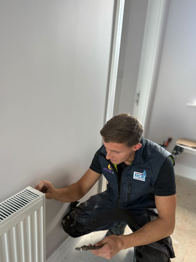 Engineer fitting a radiator on a domestic heating install